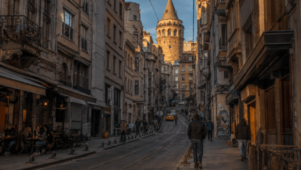 Karakoy street at evening with tram tracks, restaurant tables and Galata Tower rising at the end of the lane