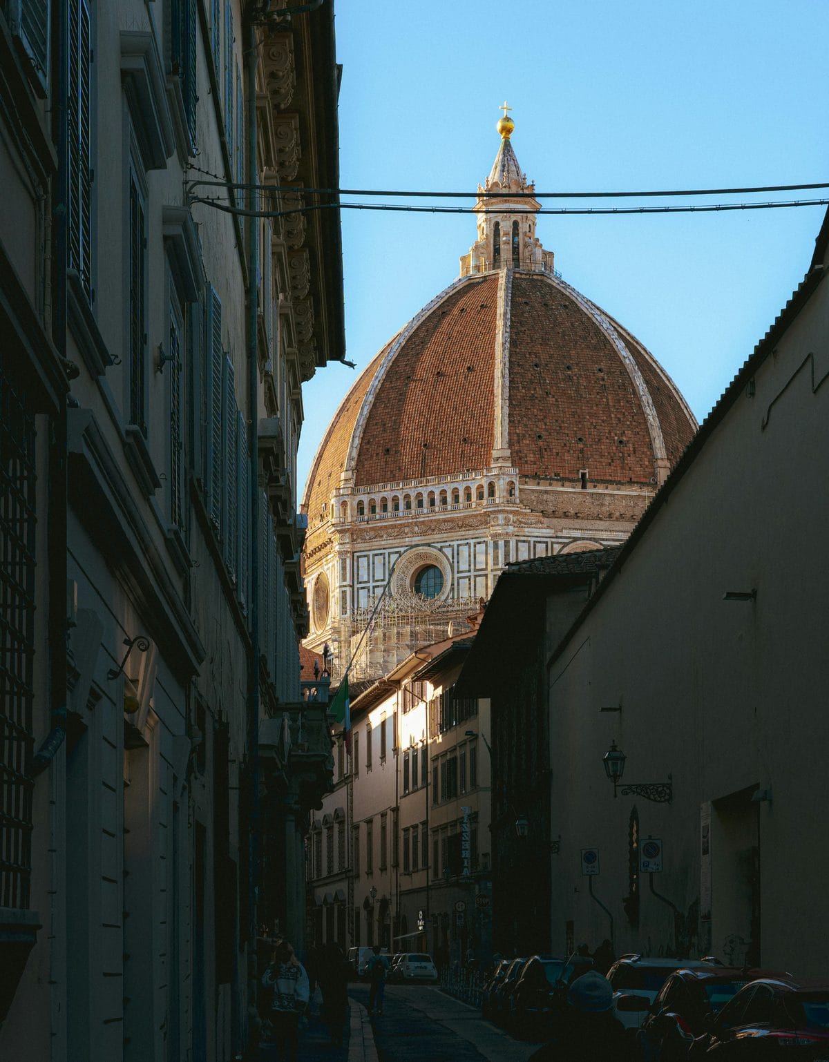 Brunelleschi's dome rising at the end of a narrow shaded street in the historic centre of Florence