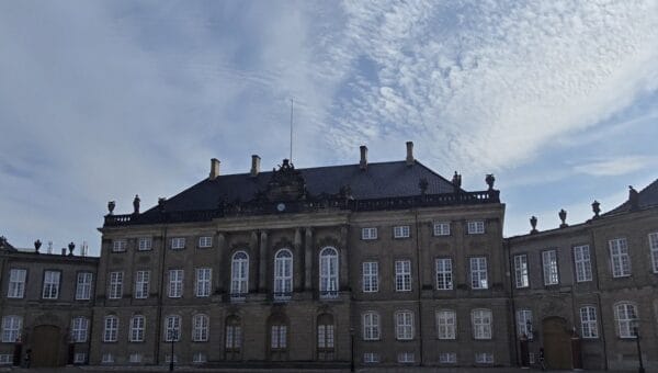 Amalienborg Palace in Copenhagen under a wide sky of high cloud, its cobbled square almost empty